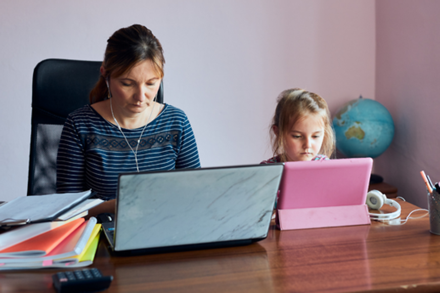 Mutter und Tochter sitzen am Schreibtisch vor ihren Laptops