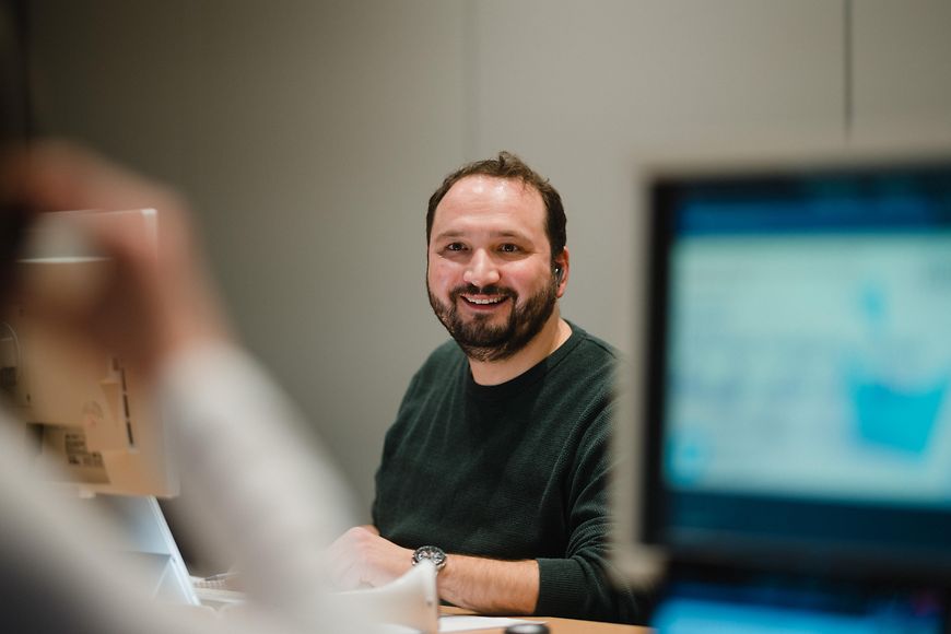 Ein lächelnder Mann der vor einem Computer sitzt