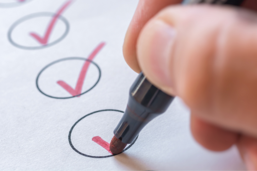 Hand mit Stift, die auf einer Checkliste Haken setzt