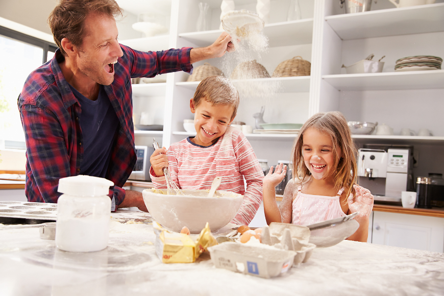 Ein Vater backt mit seinen beiden Kindern